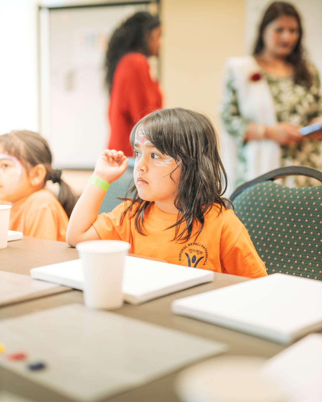 A girl seated at a table during a workshop, listening to the room.