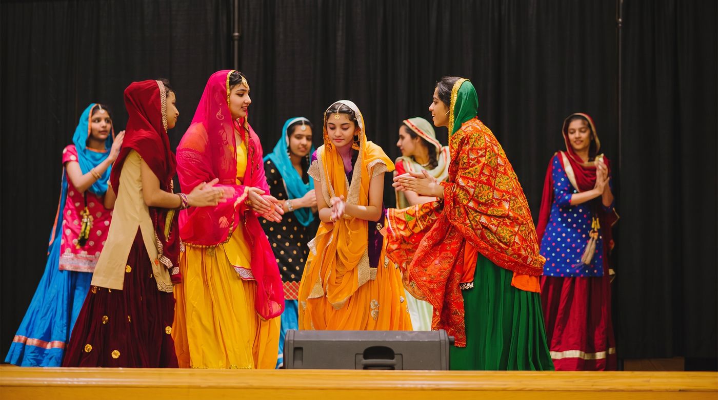 Students in traditional dress performing together on stage at Mother Language Day.