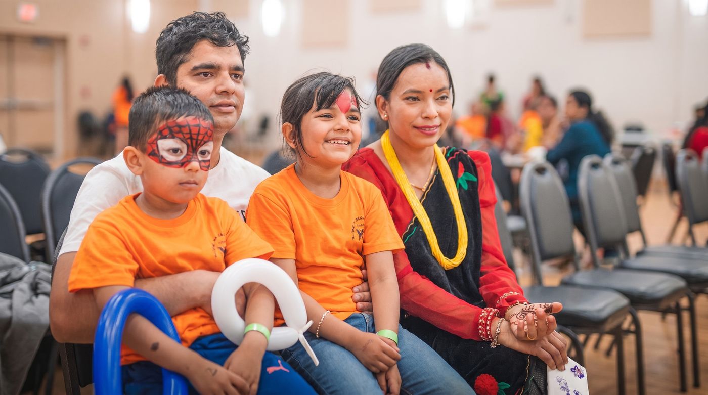 A parent and two children in IHLA T-shirts at a community event.