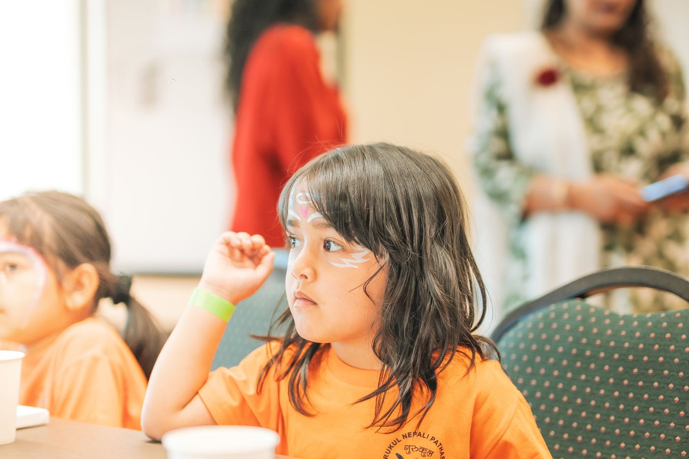 A girl seated at a workshop table, listening, blank canvases in front of her.